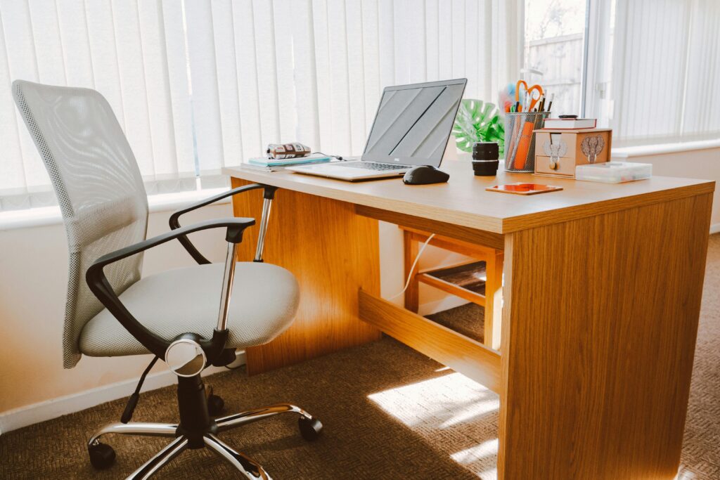 pexels-photo-1957478-1957478 A modern office workspace featuring a wooden desk, chair, laptop, and bright natural light.