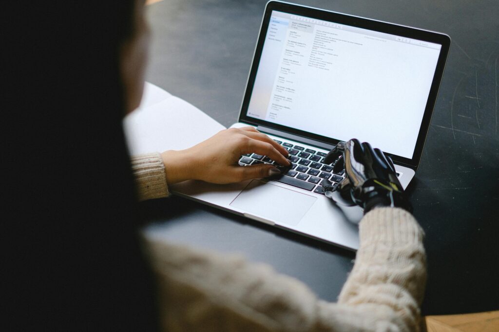 pexels-photo-5614124-5614124 A person with a prosthetic hand using a laptop, showcasing technology and inclusivity.